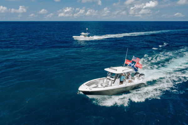 Two boats with people driving through blue water