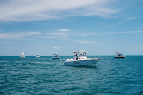 Multiple Everglades boats cruising on the open water under a clear blue sky
