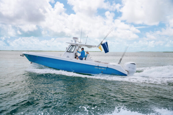 An Everglades boat speeding across the water with two people on board and fishing rods visible under a partly cloudy sky