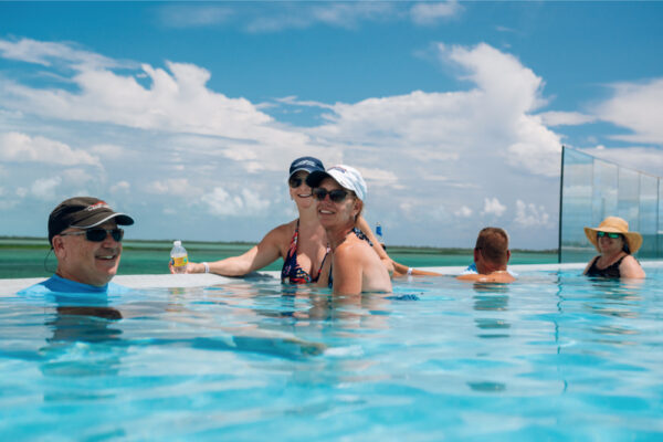 Group of people relaxing in an infinity pool under a sunny sky