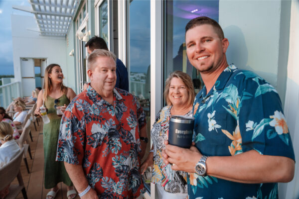 A group of people in floral shirts at a social gathering on a balcony
