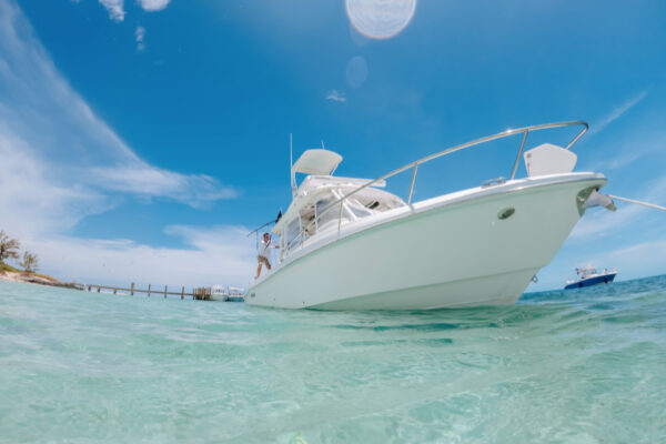 A white boat floating on clear turquoise water with a bright blue sky in the background