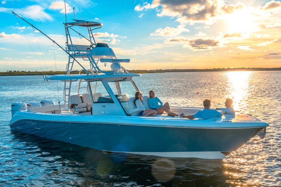 two couples relaxing on the bow of a 375cc with the sun setting in the background