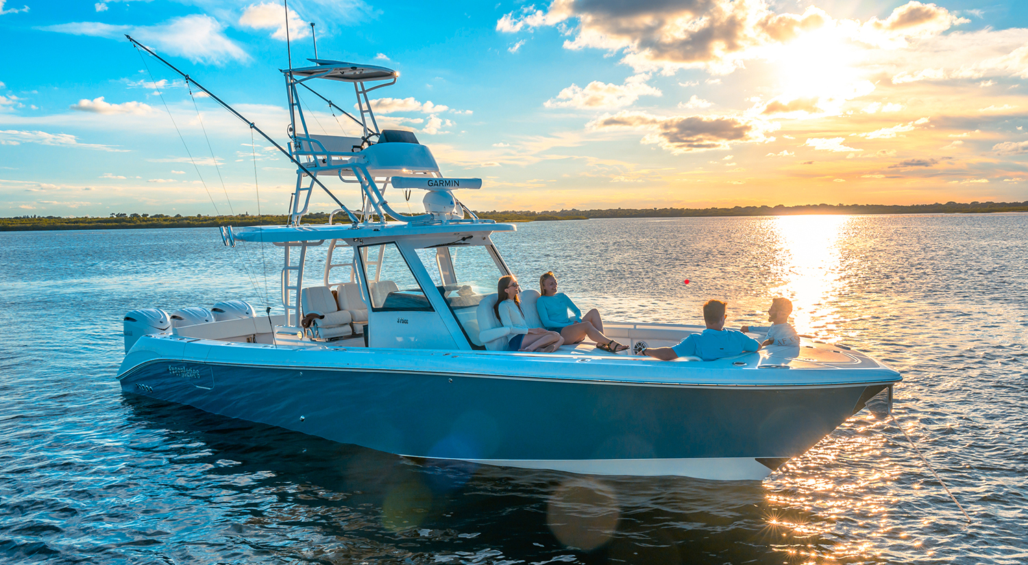 two couples relaxing on the bow of a 375cc with the sun setting in the background